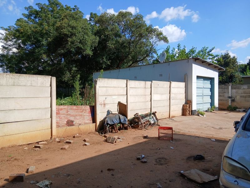 Rear exterior view showing a detached garage and a precast concrete boundary wall with an unpaved yard area.