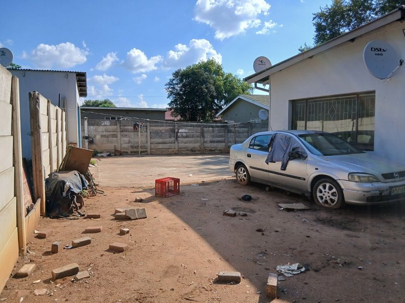 Rear exterior area featuring a concrete driveway and perimeter precast concrete boundary walls.