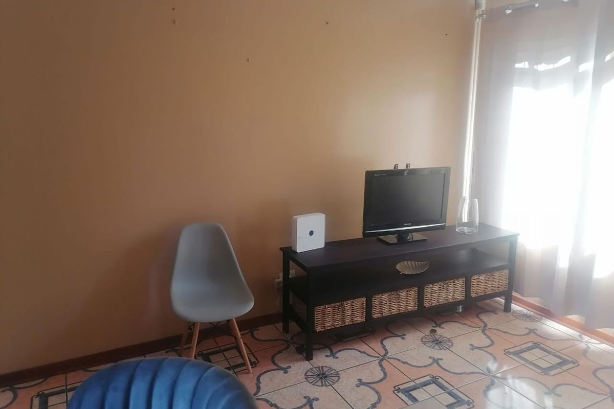 A living room area featuring decorative tiled flooring and access to a patio through a sliding glass door.