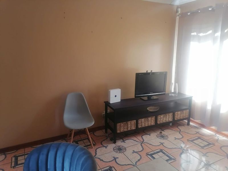 A living room area featuring decorative tiled flooring and access to a patio through a sliding glass door.