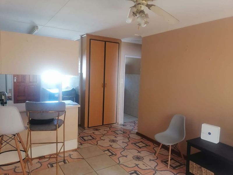 Open plan living area featuring tiled flooring, a built-in cupboard, and a breakfast counter connecting to the kitchen space.