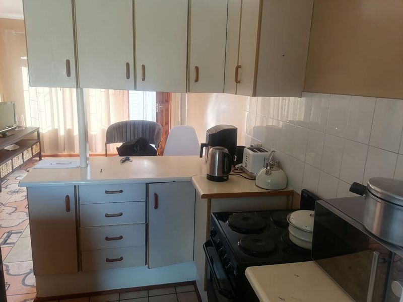 A compact kitchen featuring laminate cabinetry, a tiled backsplash, and an integrated electric stove with a functional breakfast counter area.