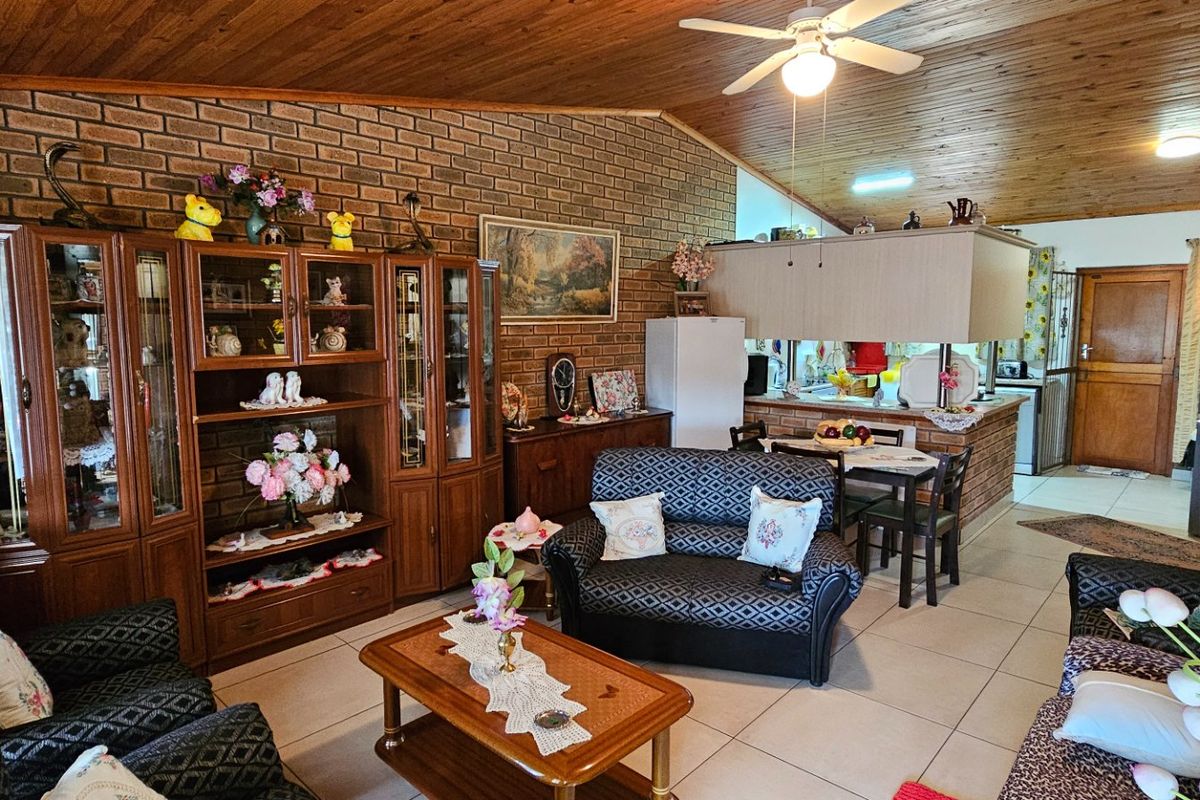 Open plan living and kitchen area featuring exposed brick walls, timber ceiling, and tiled flooring, offering a functional layout with a breakfast counter.