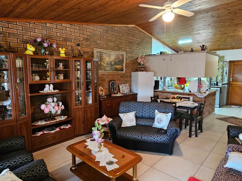 Open plan living and kitchen area featuring exposed brick walls, timber ceiling, and tiled flooring, offering a functional layout with a breakfast counter.