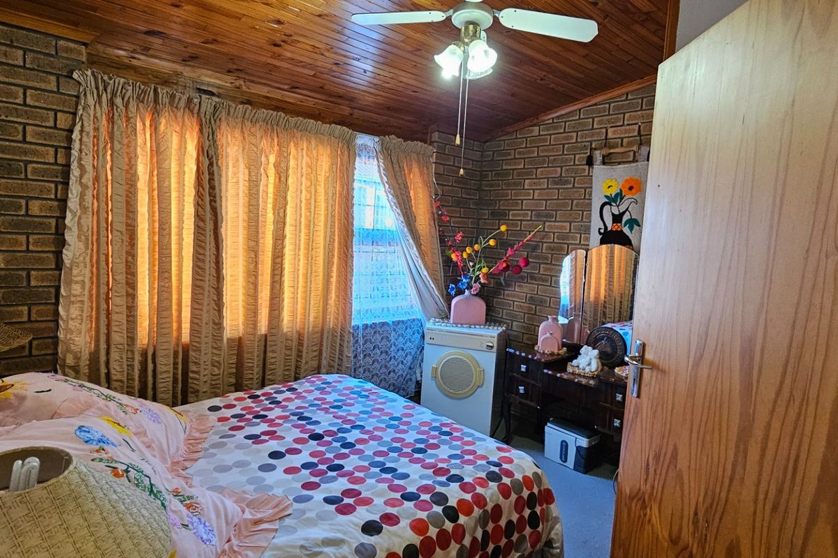A bedroom featuring exposed brick walls and a timber tongue and groove ceiling, providing a rustic aesthetic.