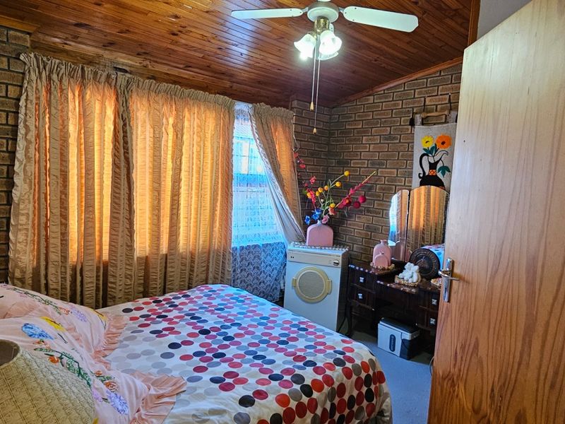 A bedroom featuring exposed brick walls and a timber tongue and groove ceiling, providing a rustic aesthetic.