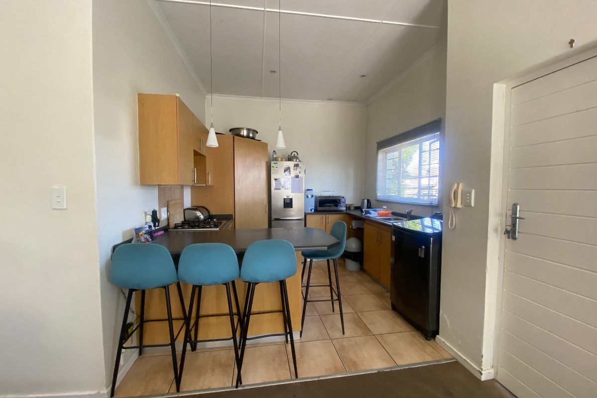 A functional kitchen featuring built-in wooden cabinetry, laminate countertops, a gas hob, and tiled flooring, offering a practical layout for daily meal preparation.