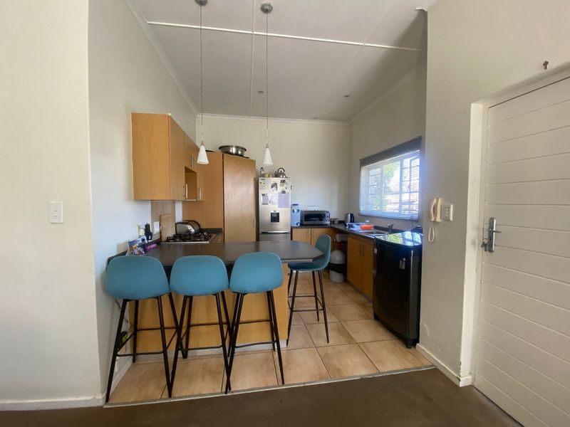 A functional kitchen featuring built-in wooden cabinetry, laminate countertops, a gas hob, and tiled flooring, offering a practical layout for daily meal preparation.