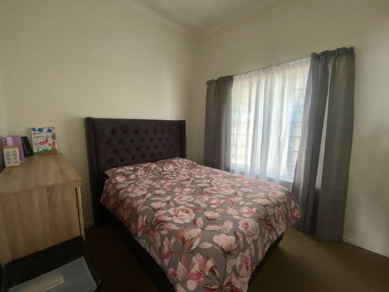 A standard bedroom featuring carpeted flooring and window treatments, providing a functional and neutral space for rest.
