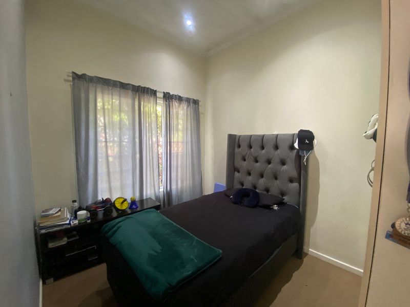 A standard bedroom featuring neutral walls, carpeted flooring, and a built-in wardrobe, offering a functional space with natural light.