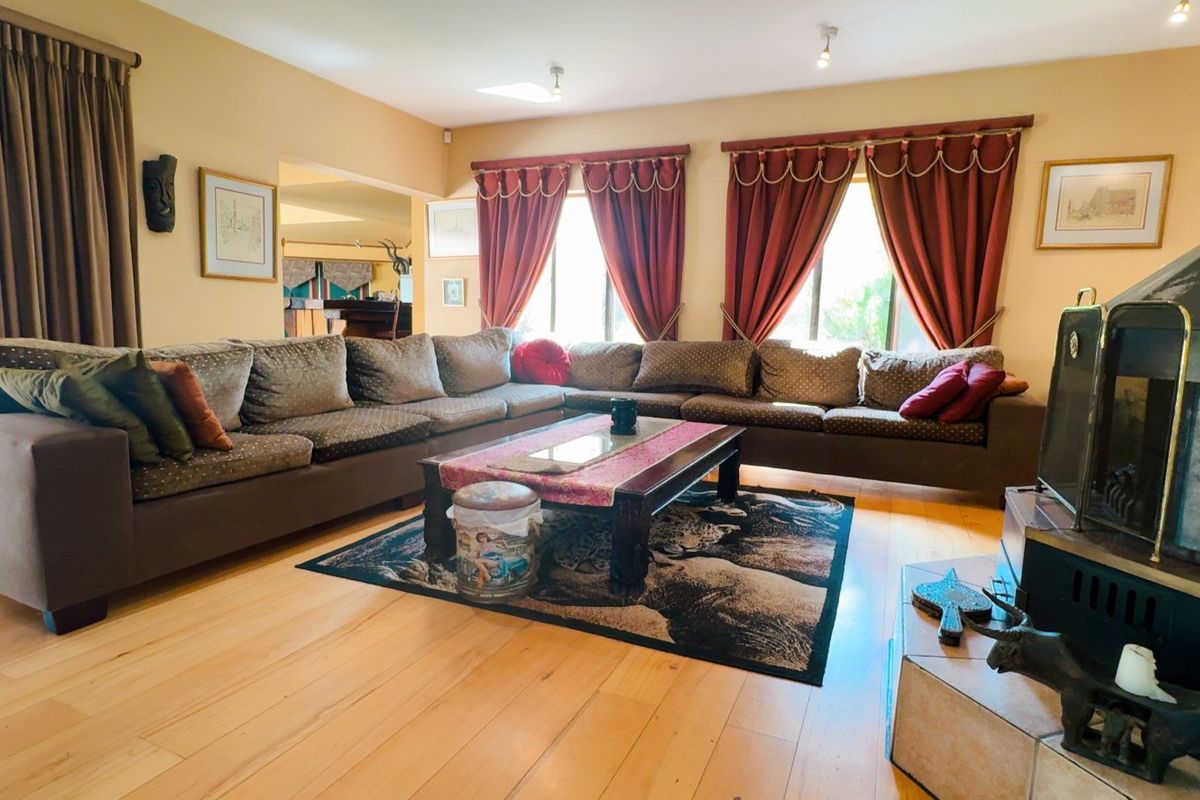 Spacious living room featuring hardwood flooring, a prominent freestanding fireplace, and direct access to an outdoor patio area through sliding glass doors.