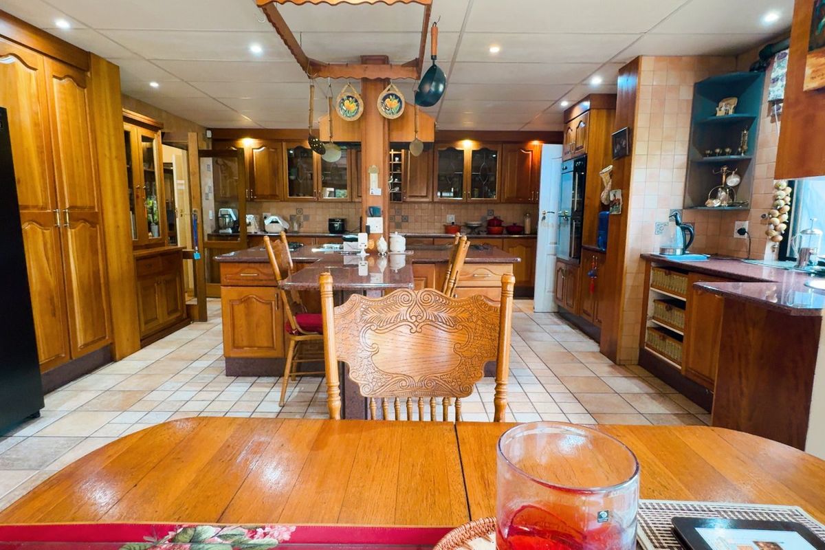 Spacious kitchen featuring extensive wooden cabinetry, granite countertops, a central island, and tiled flooring, offering a traditional aesthetic with ample storage and workspace.