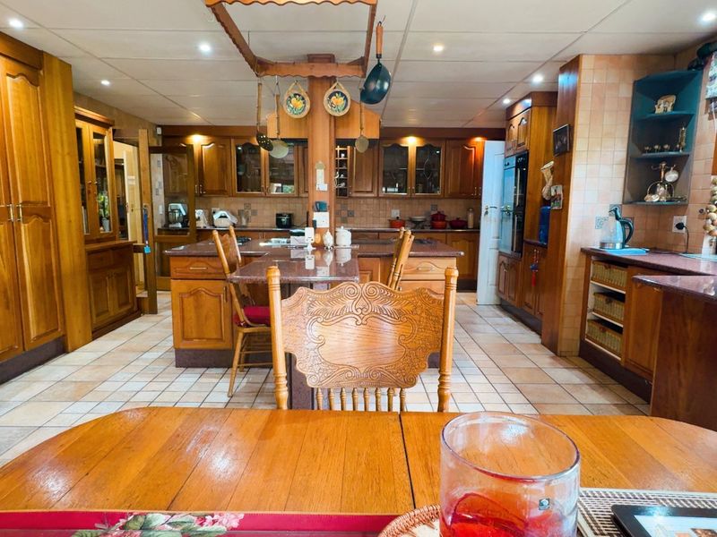 Spacious kitchen featuring extensive wooden cabinetry, granite countertops, a central island, and tiled flooring, offering a traditional aesthetic with ample storage and workspace.