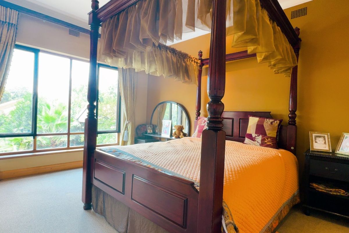 A spacious bedroom featuring large windows that provide natural light and carpeted flooring, offering a comfortable and well-proportioned living space.