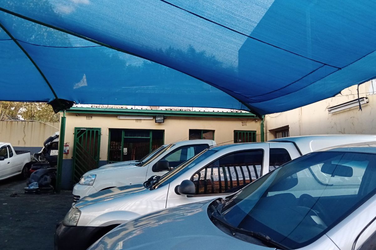 Rear exterior area featuring a large blue shade cloth canopy structure providing covered parking space for multiple vehicles.