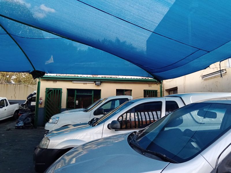 Rear exterior area featuring a large blue shade cloth canopy structure providing covered parking space for multiple vehicles.