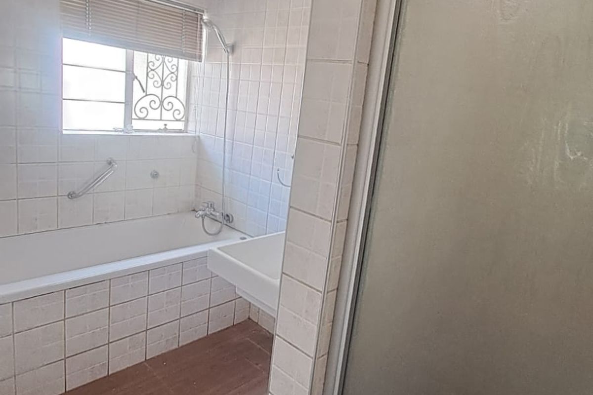 A functional bathroom featuring a built-in bathtub, separate shower enclosure, and tiled flooring, offering a clean and practical layout.