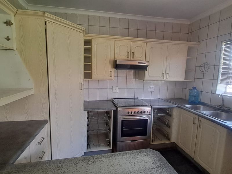 A functional kitchen featuring built-in cabinetry, a stainless steel stove with extractor fan, double basin sink, and tiled backsplash.