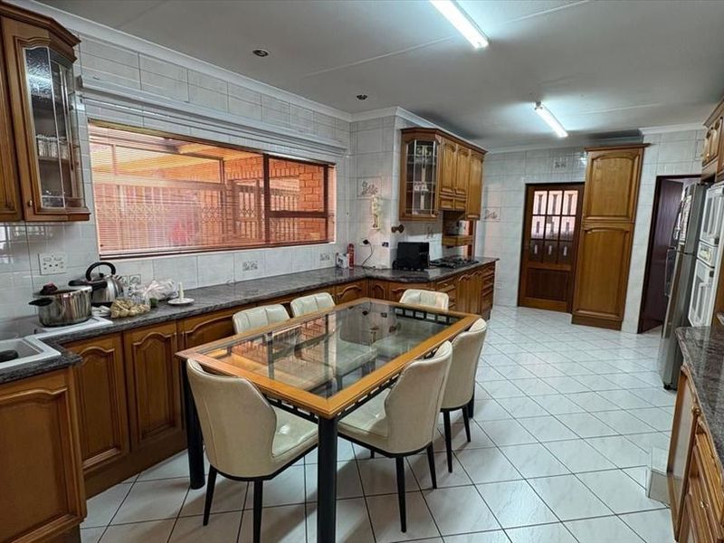 Spacious kitchen featuring traditional wooden cabinetry, granite countertops, tiled flooring, and a dedicated dining area with ample storage space.