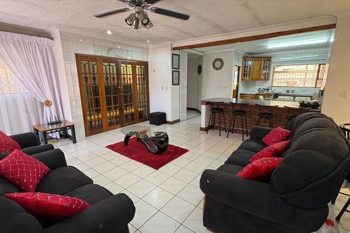 Open plan living area featuring tiled floors, a breakfast bar with brick detailing, and a kitchen with wooden cabinetry.