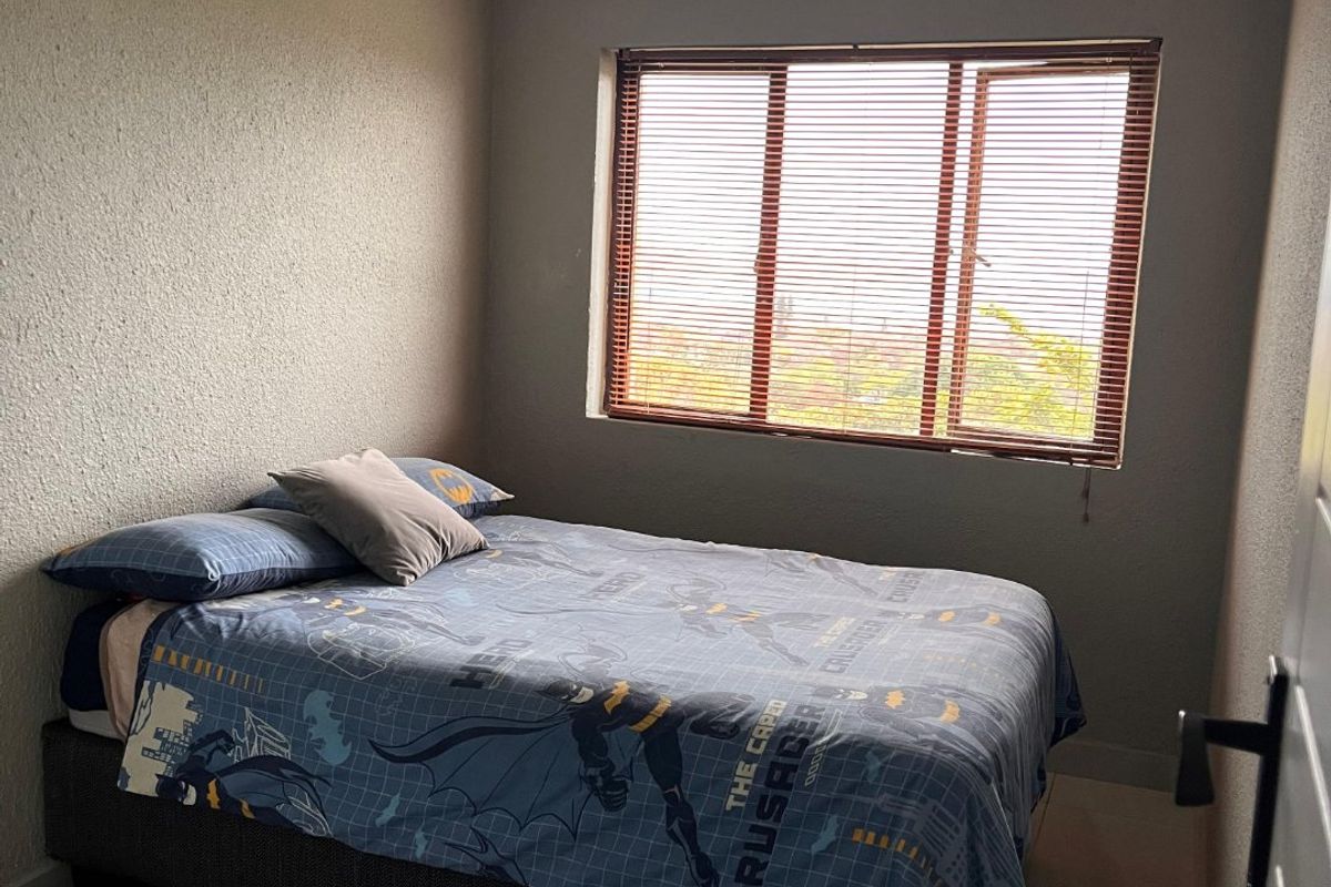 A functional bedroom featuring tiled flooring, a window with fitted blinds, and a standard ceiling light fixture.