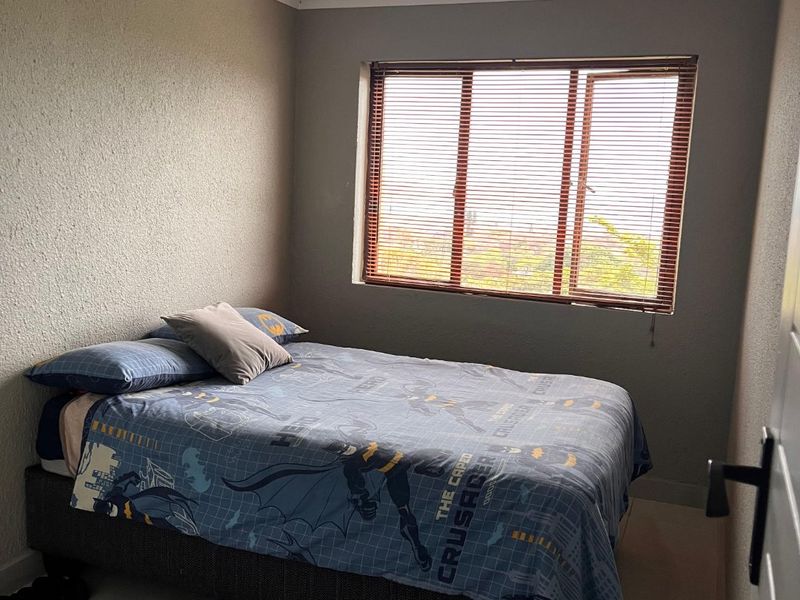 A functional bedroom featuring tiled flooring, a window with fitted blinds, and a standard ceiling light fixture.