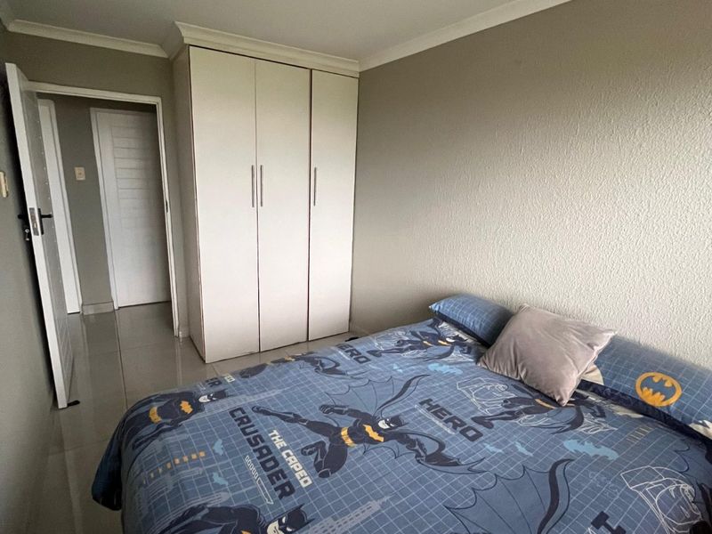 A bedroom featuring built-in white cabinetry and tiled flooring, providing a functional space with neutral wall finishes.