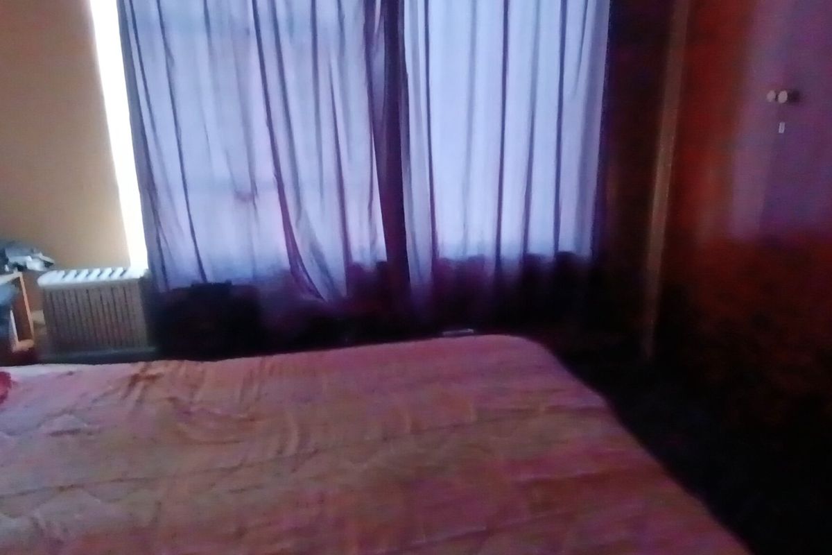 A bedroom featuring a built-in wardrobe and window with curtains.