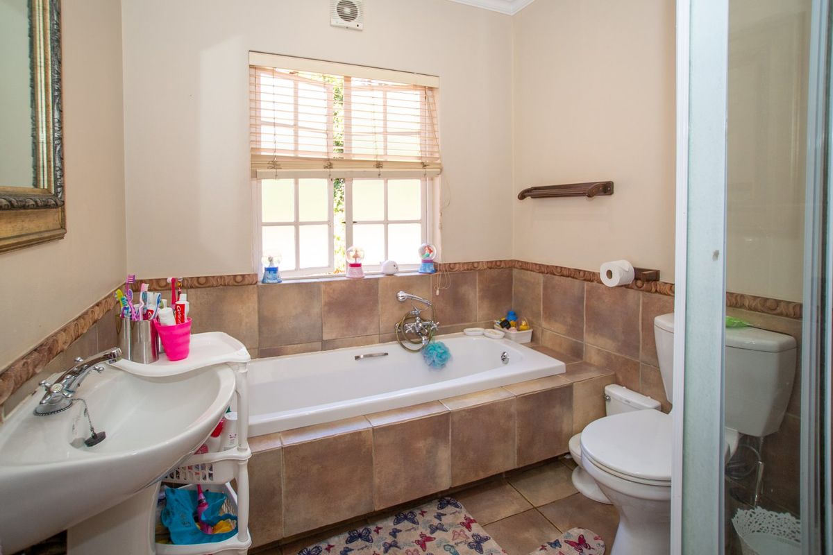 A functional bathroom featuring a bathtub, pedestal basin, toilet, and a separate shower enclosure with tiled wall finishes.