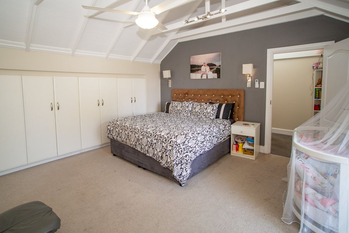Spacious bedroom featuring a vaulted ceiling with a ceiling fan, extensive built-in cupboard storage, and integrated lighting fixtures.