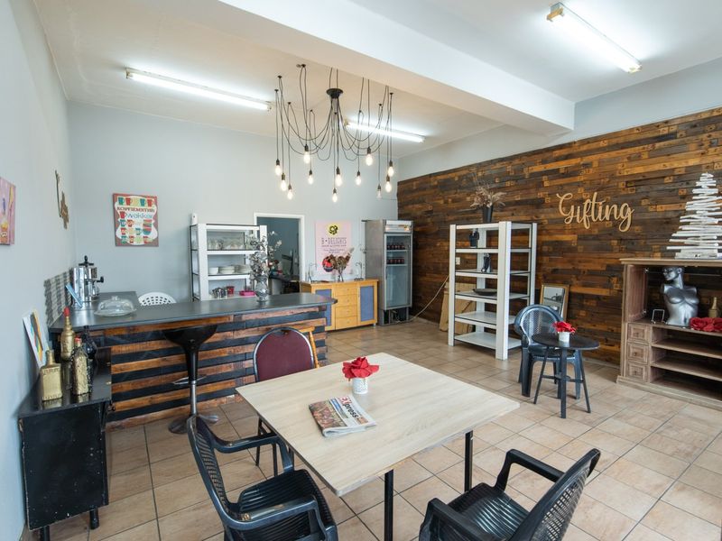 Open-plan commercial space featuring a service counter, timber accent wall, tiled flooring, and a mix of fluorescent and decorative pendant lighting.