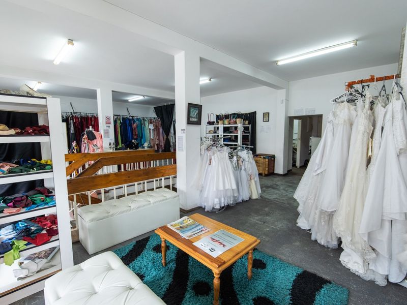 A commercial retail space featuring open-plan layout, concrete flooring, and fluorescent lighting, currently utilized as a bridal boutique.