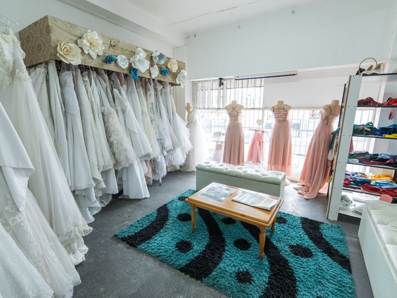 Commercial retail space featuring built-in clothing display rails and large windows with security bars, suitable for a boutique or showroom environment.