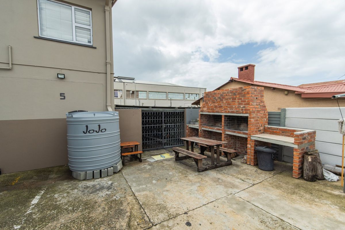 Rear exterior area featuring a built-in brick braai, concrete paving, and a water storage tank, providing a functional outdoor space.