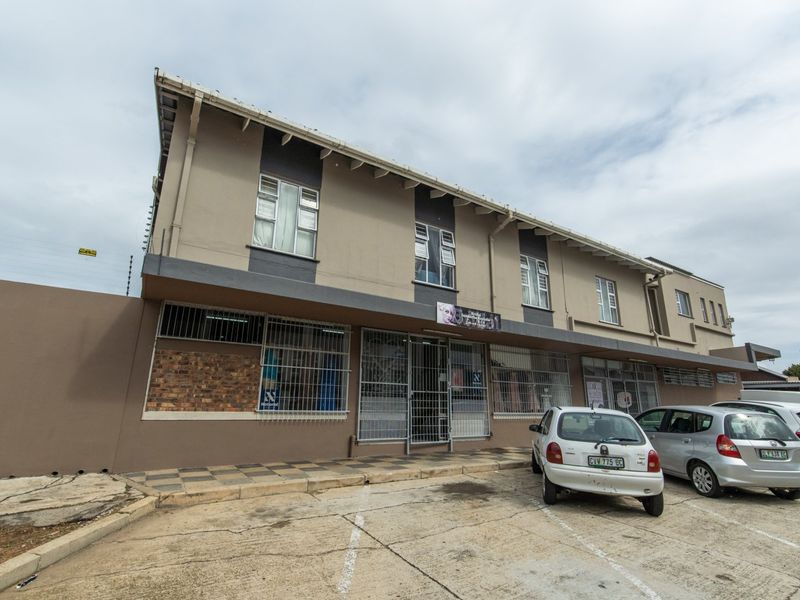 Front elevation of a commercial building featuring a paved parking area, security gates, and electric fencing.