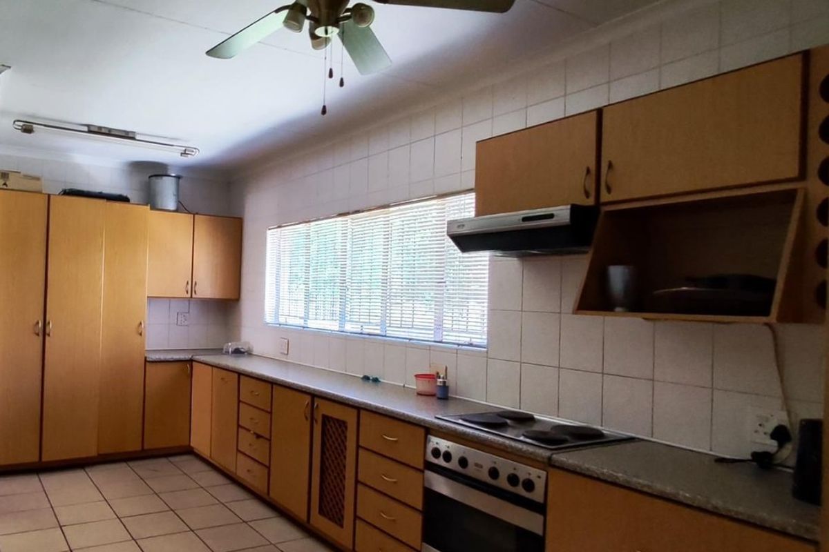 A functional kitchen featuring extensive built-in cabinetry, laminate countertops, integrated oven and hob, and tiled flooring throughout.