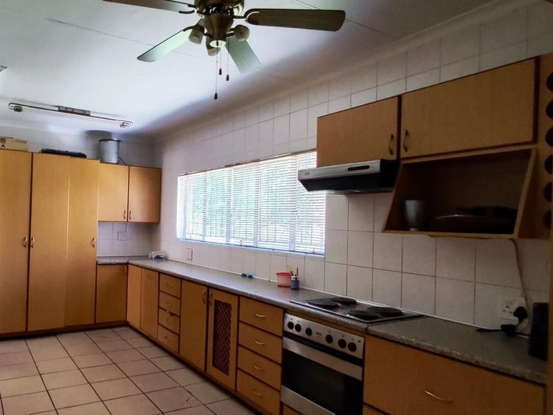 A functional kitchen featuring extensive built-in cabinetry, laminate countertops, integrated oven and hob, and tiled flooring throughout.