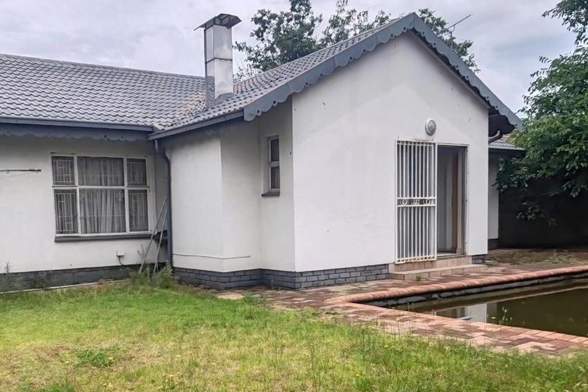 Rear view of the house featuring a swimming pool, brick paved surround, and a security gate entrance.