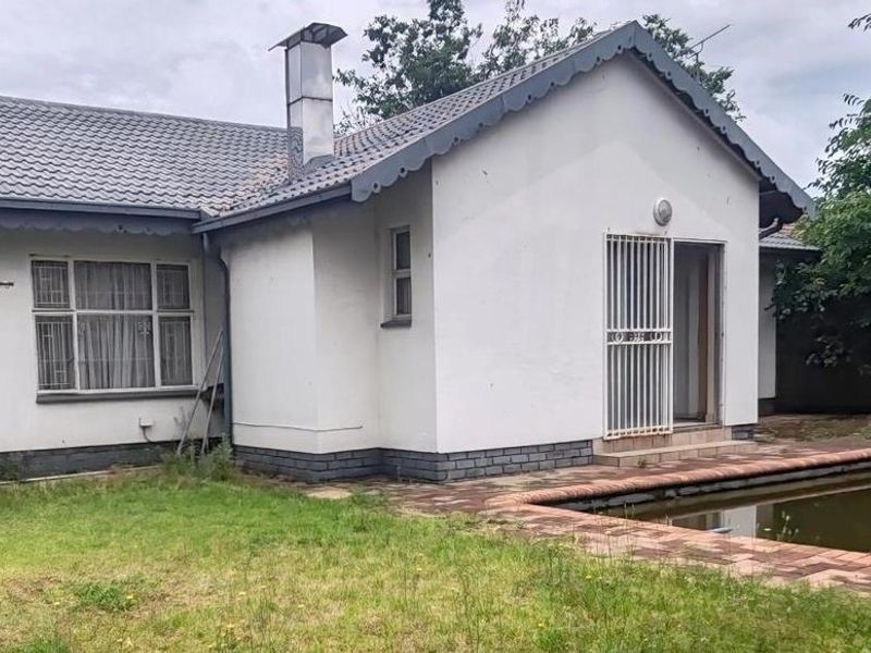 Rear view of the house featuring a swimming pool, brick paved surround, and a security gate entrance.
