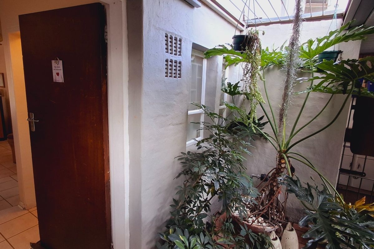 A covered patio or courtyard area featuring tiled flooring, a solid timber door, and ventilation bricks, providing a semi-enclosed outdoor space.
