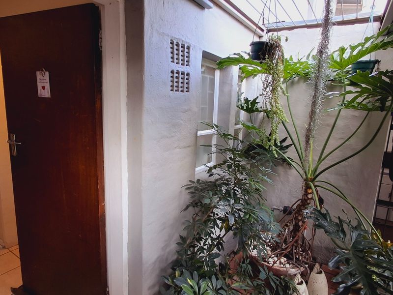 A covered patio or courtyard area featuring tiled flooring, a solid timber door, and ventilation bricks, providing a semi-enclosed outdoor space.