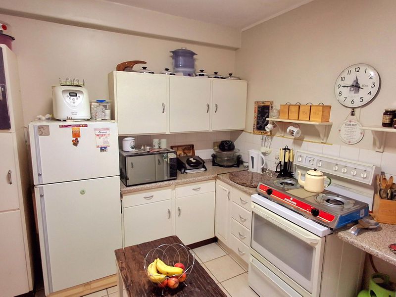 A functional kitchen featuring white cabinetry, laminate countertops, a tiled backsplash, and a freestanding stove, offering a practical layout for daily meal preparation.