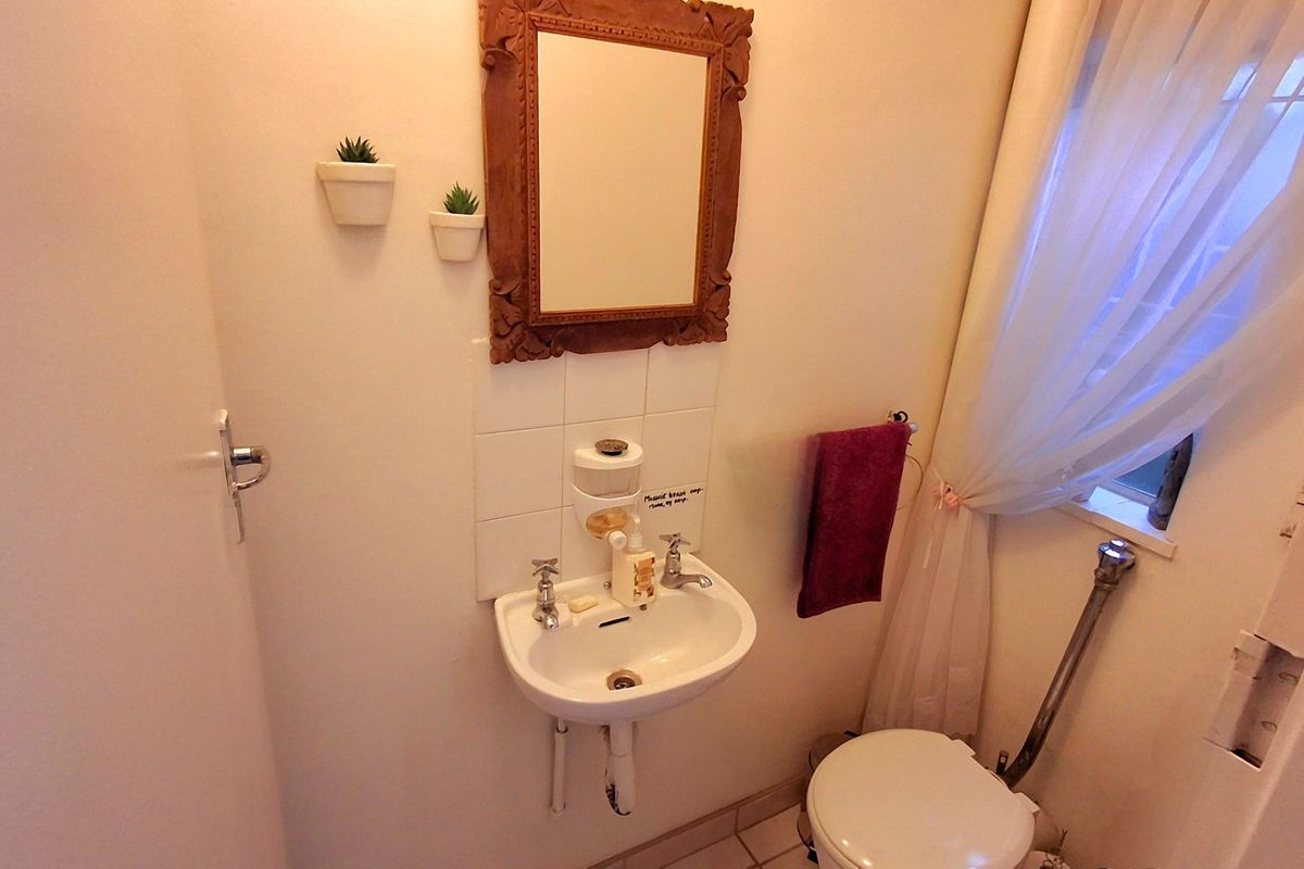 Compact bathroom featuring a wall-mounted basin with tiled splashback and a standard toilet, requiring minor cosmetic updates to finishes and plumbing concealment.