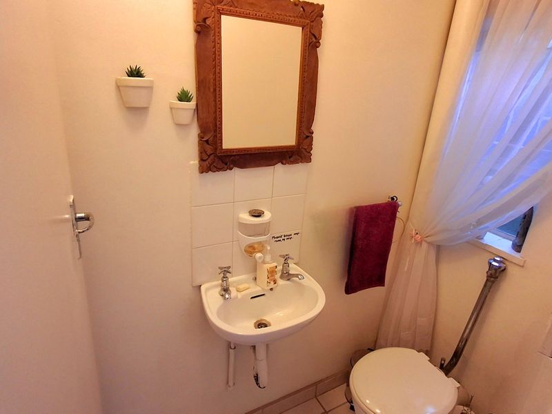 Compact bathroom featuring a wall-mounted basin with tiled splashback and a standard toilet, requiring minor cosmetic updates to finishes and plumbing concealment.