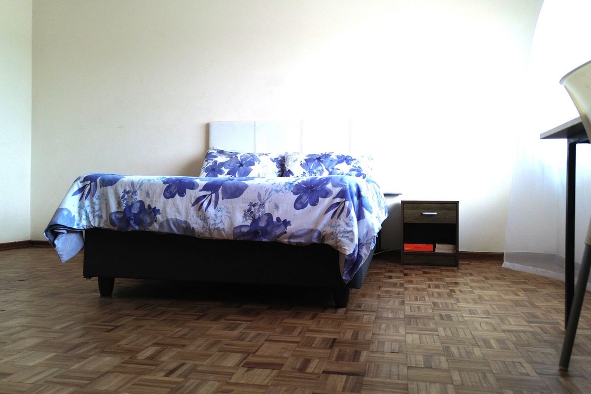 A bedroom featuring classic parquet flooring and neutral wall finishes, offering a blank canvas for personalization.