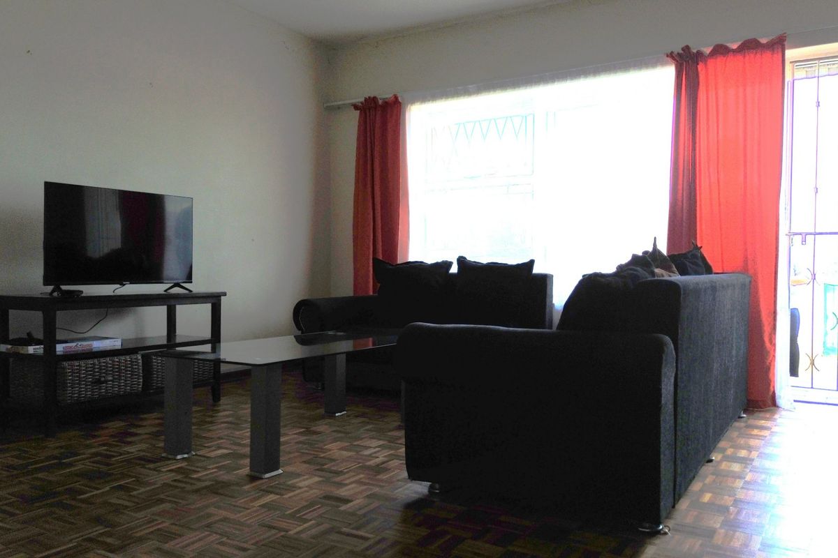 A living room featuring classic parquet flooring and direct access to an outdoor area through a security gate.