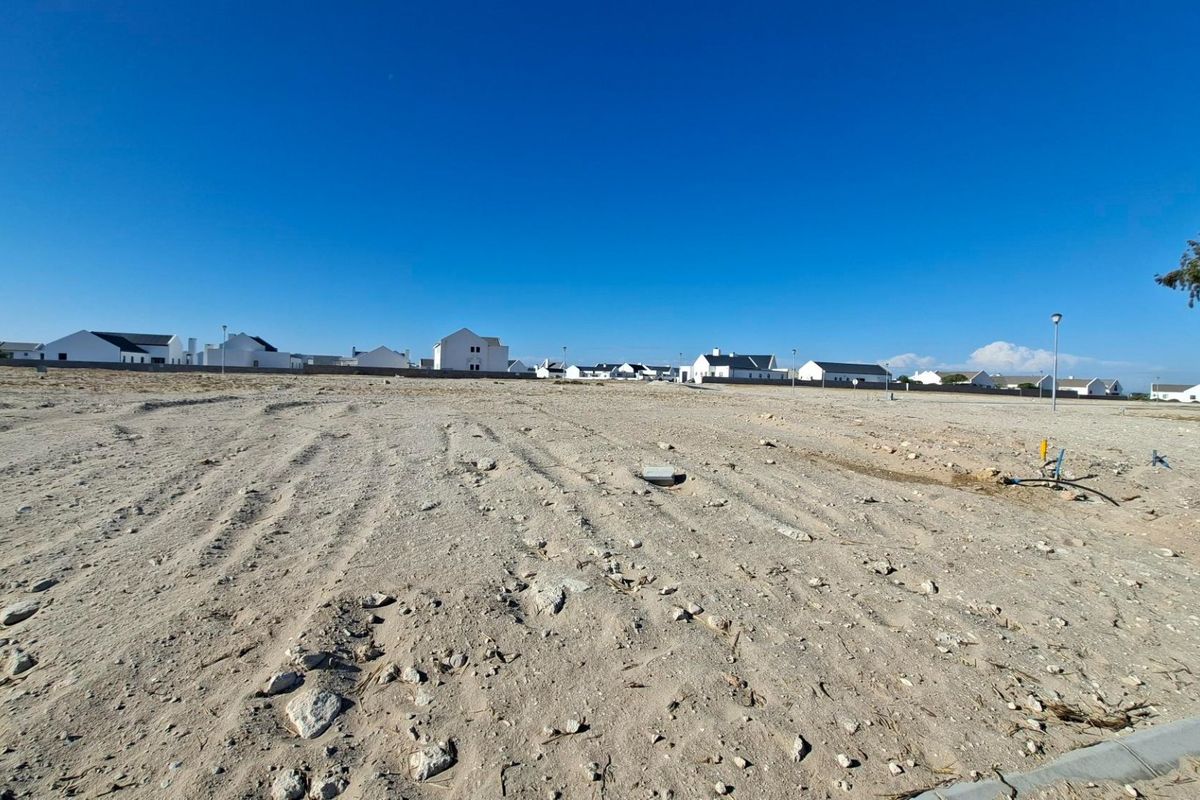 A vacant residential plot of land featuring cleared sandy terrain, ready for development within an established residential estate.