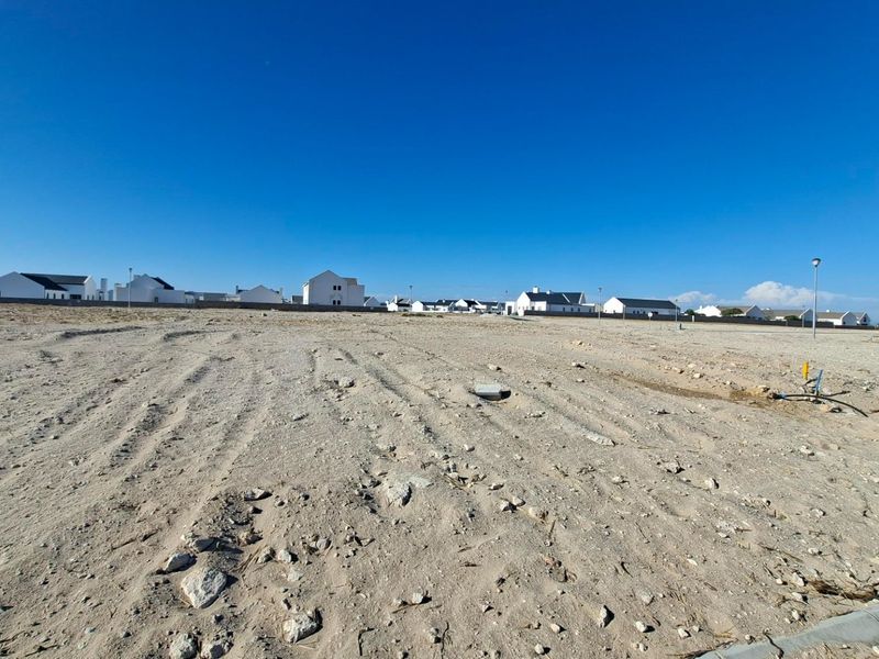 A vacant residential plot of land featuring cleared sandy terrain, ready for development within an established residential estate.