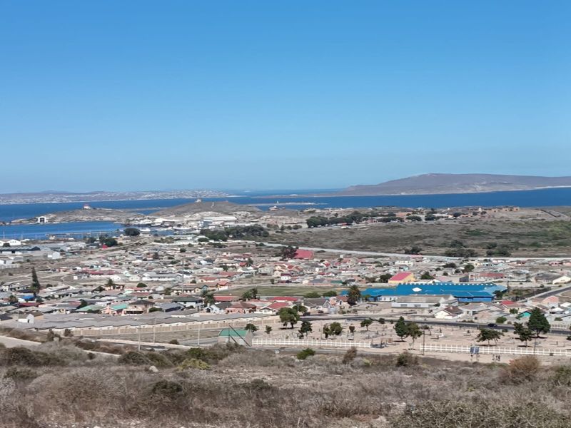 A wide-angle elevated view overlooking a coastal residential area and the surrounding landscape.