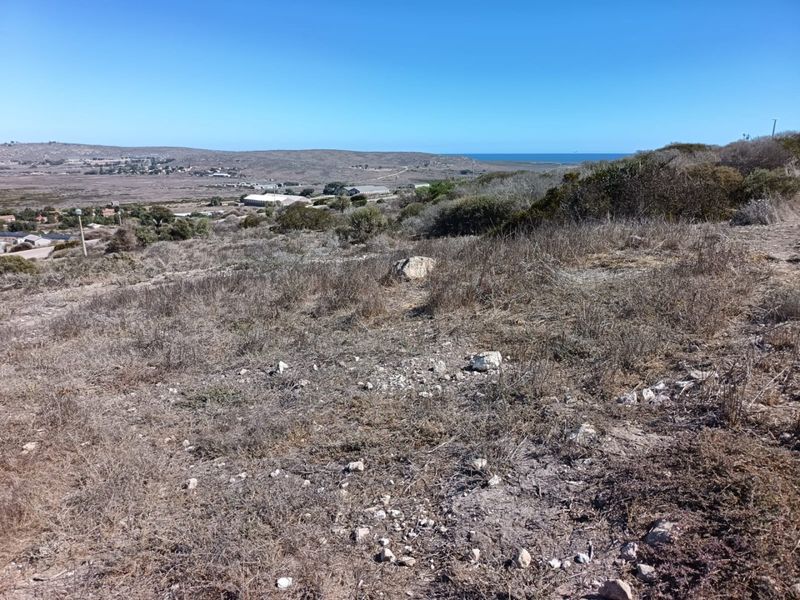 A wide-angle view of the vacant residential land, showcasing the natural coastal landscape and surrounding terrain.